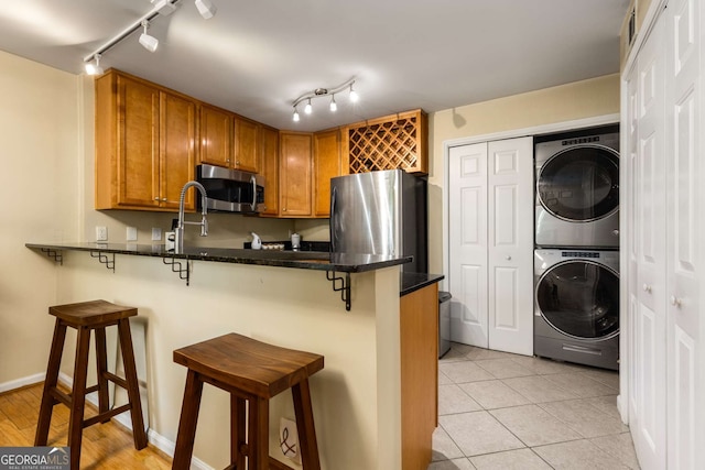 1445 Monroe Dr Unit 14B, Atlanta, GA 30324 - kitchen featuring stainless steel appliances, stacked washer / drying machine, track lighting, a peninsula, and a breakfast bar area