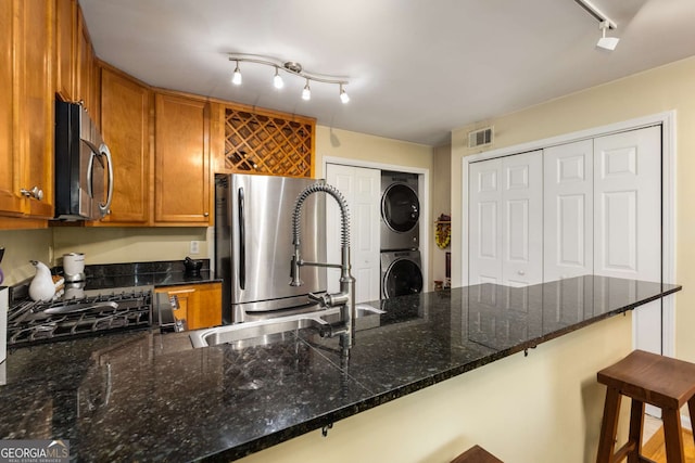 1445 Monroe Dr Unit 14B, Atlanta, GA 30324 - kitchen with estacked washer and dryer, track lighting, freestanding refrigerator, brown cabinets, and a kitchen bar