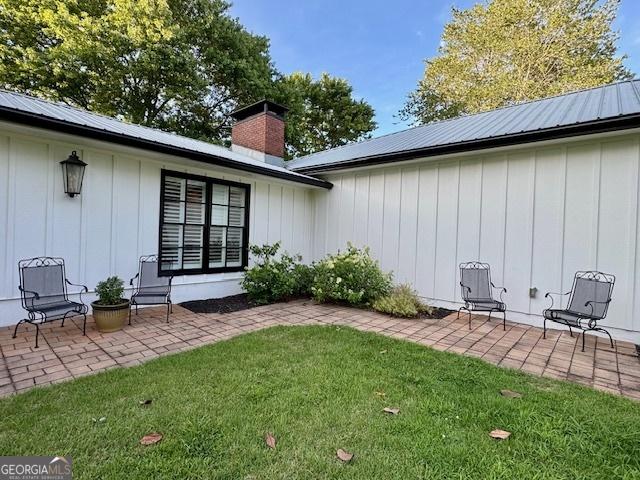 360 Morgan Mill Rd, Brooks, GA 30205 - back of property featuring board and batten siding, a patio area, a lawn, and a chimney