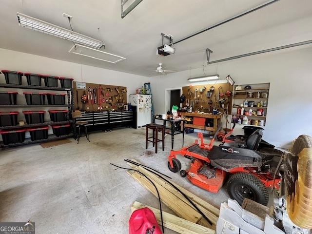 360 Morgan Mill Rd, Brooks, GA 30205 - garage featuring a workshop area, freestanding refrigerator, a garage door opener, and a ceiling fan