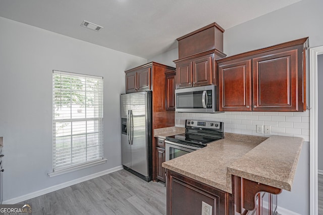 231 Cyane Ln, Guyton, GA 31312 - kitchen with appliances with stainless steel finishes, tasteful backsplash, a peninsula, light wood finished floors, and a breakfast bar area