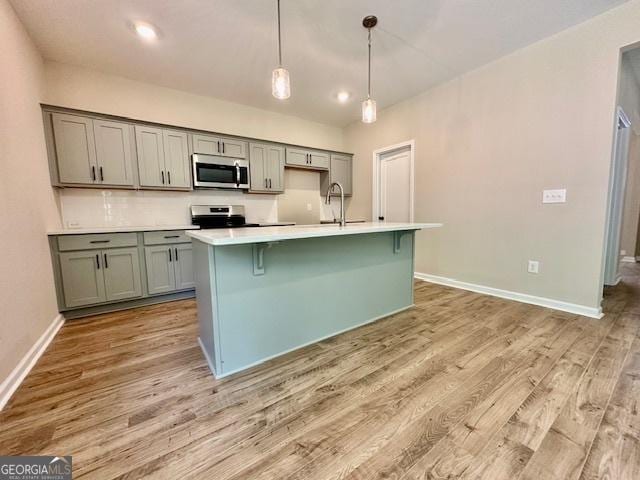 202 Lakeside Dr Lot 73, Lagrange, GA 30240 - kitchen featuring appliances with stainless steel finishes, light wood-type flooring, light countertops, a kitchen island with sink, and a kitchen bar