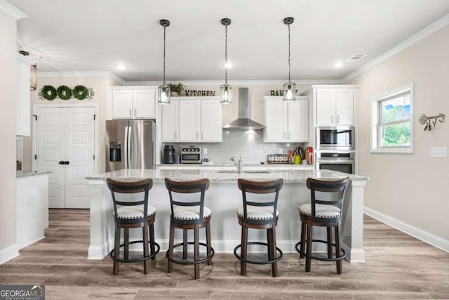 2326 Britt St, Grayson, GA 30017 - kitchen with appliances with stainless steel finishes, wall chimney range hood, white cabinetry, a center island with sink, and crown molding