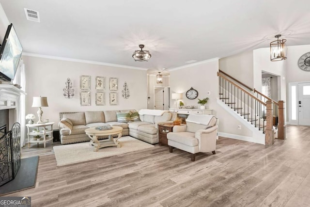 2326 Britt St, Grayson, GA 30017 - living area featuring stairs, wood finished floors, crown molding, a fireplace with raised hearth, and a chandelier