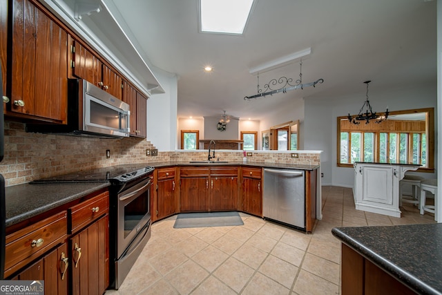 124 Old Salem Trl, Pine Mountain, GA 31822 - kitchen featuring appliances with stainless steel finishes, decorative backsplash, light tile patterned flooring, brown cabinetry, and dark countertops