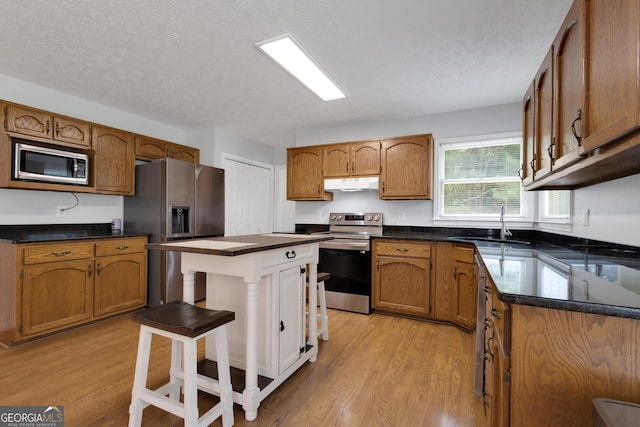 115 Rockhurst Chase, Tyrone, GA 30290 - kitchen featuring stainless steel appliances, under cabinet range hood, light wood finished floors, dark countertops, and a textured ceiling