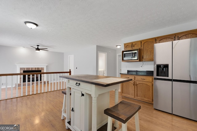 115 Rockhurst Chase, Tyrone, GA 30290 - kitchen featuring appliances with stainless steel finishes, ceiling fan, light wood finished floors, a textured ceiling, and brown cabinetry
