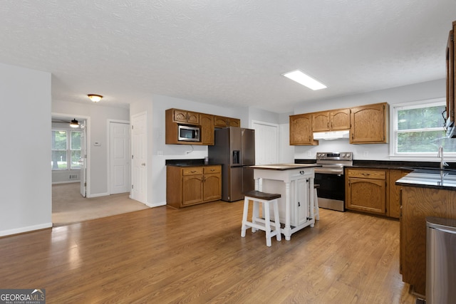 115 Rockhurst Chase, Tyrone, GA 30290 - kitchen featuring appliances with stainless steel finishes, under cabinet range hood, a kitchen island, dark countertops, and light wood-style floors