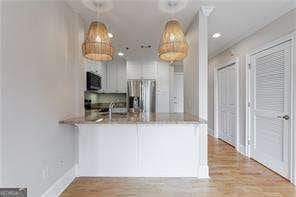 2255 Peachtree Rd NE Unit 620, Atlanta, GA 30309 - kitchen featuring freestanding refrigerator, a peninsula, wood finished floors, and hanging light fixtures