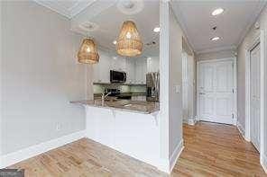 2255 Peachtree Rd NE Unit 620, Atlanta, GA 30309 - kitchen with appliances with stainless steel finishes, a peninsula, a breakfast bar area, ornamental molding, and wood finished floors