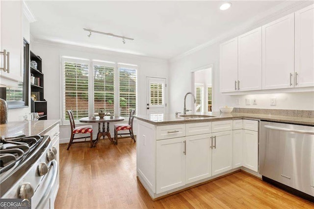 1117 Haven Glen Ln NE, Brookhaven, GA 30319 - kitchen with appliances with stainless steel finishes, white cabinets, light wood-style flooring, a peninsula, and healthy amount of natural light