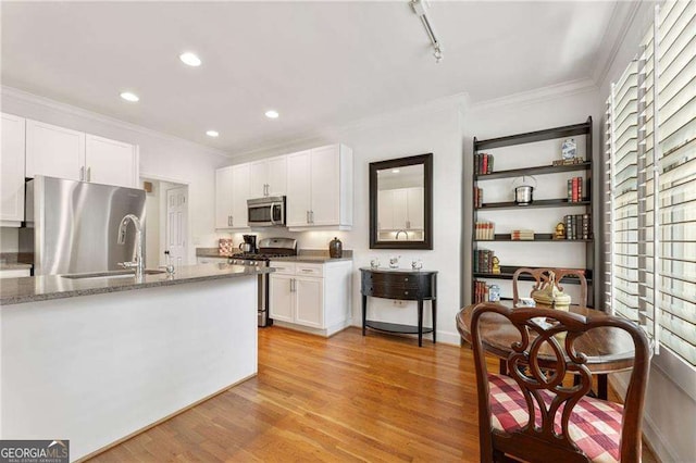 1117 Haven Glen Ln NE, Brookhaven, GA 30319 - kitchen with appliances with stainless steel finishes, crown molding, white cabinets, light wood finished floors, and light stone counters