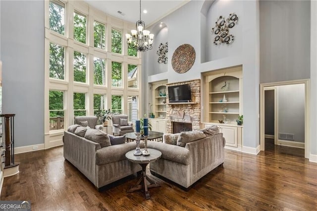 217 Fernwood Pl, Woodstock, GA 30188 - living room with a towering ceiling, built in features, a stone fireplace, a chandelier, and dark wood finished floors