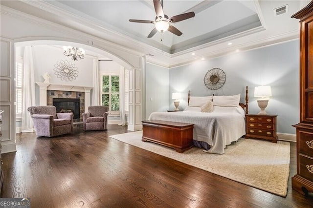 217 Fernwood Pl, Woodstock, GA 30188 - bedroom featuring wood finished floors, crown molding, a glass covered fireplace, arched walkways, and a tray ceiling