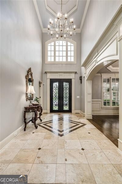 217 Fernwood Pl, Woodstock, GA 30188 - foyer with ornamental molding, a towering ceiling, arched walkways, french doors, and a chandelier