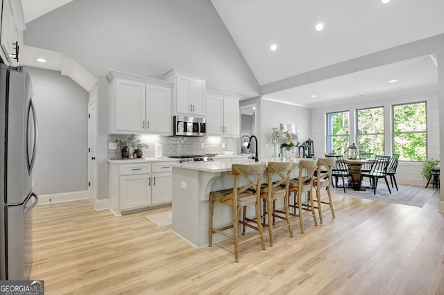 192 Greyfairs Ave, Senoia, GA 30276 - kitchen featuring stainless steel appliances, light wood-style floors, light countertops, a breakfast bar area, and high vaulted ceiling