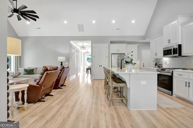 192 Greyfairs Ave, Senoia, GA 30276 - kitchen featuring appliances with stainless steel finishes, open floor plan, a center island with sink, decorative backsplash, and a ceiling fan