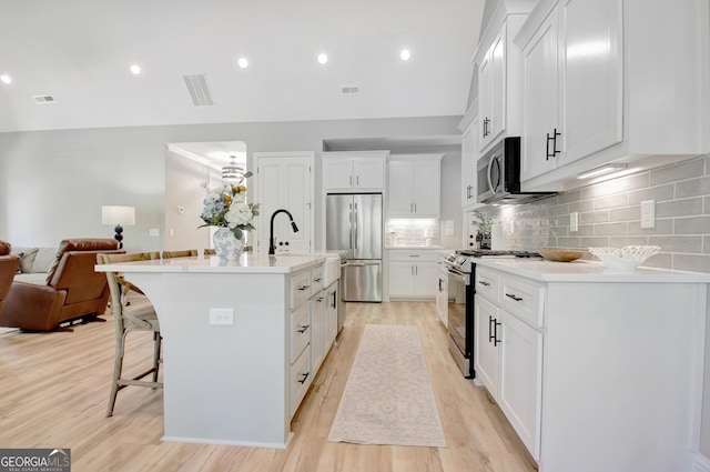 192 Greyfairs Ave, Senoia, GA 30276 - kitchen with appliances with stainless steel finishes, open floor plan, a breakfast bar area, light wood-style flooring, and a kitchen island with sink