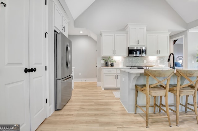 192 Greyfairs Ave, Senoia, GA 30276 - kitchen featuring appliances with stainless steel finishes, lofted ceiling, backsplash, light countertops, and recessed lighting