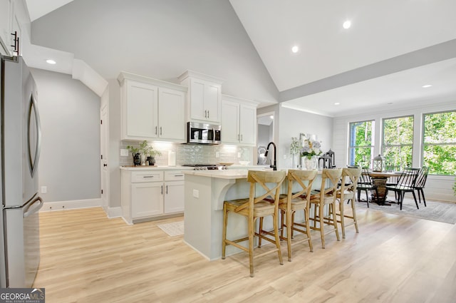 192 Greyfairs Ave, Senoia, GA 30276 - kitchen with appliances with stainless steel finishes, light wood finished floors, a kitchen breakfast bar, light countertops, and an island with sink