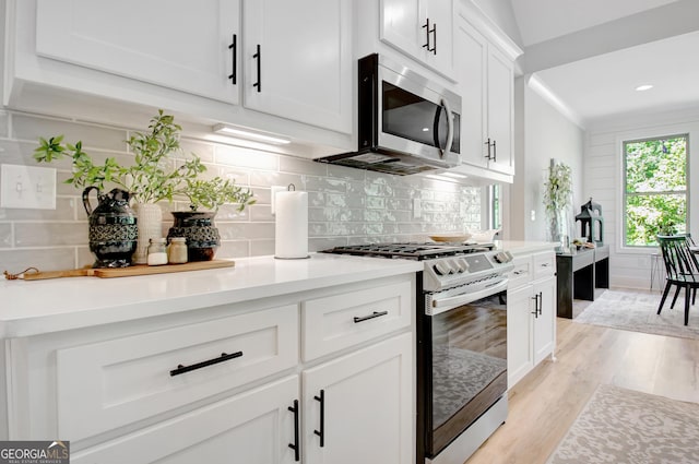 192 Greyfairs Ave, Senoia, GA 30276 - kitchen with appliances with stainless steel finishes, light wood-type flooring, plenty of natural light, white cabinetry, and ornamental molding