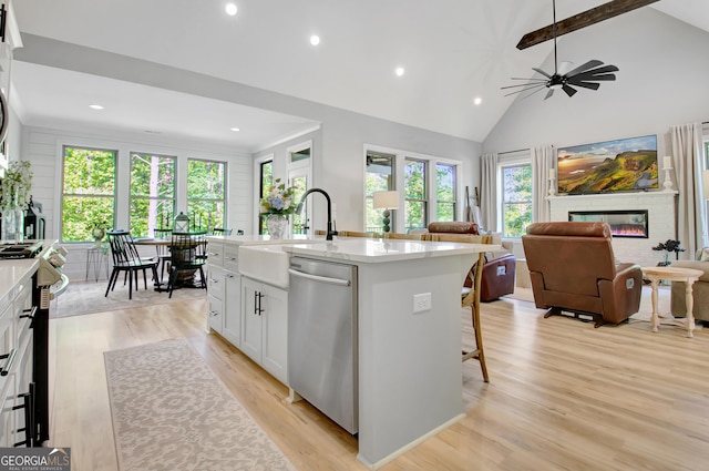 192 Greyfairs Ave, Senoia, GA 30276 - kitchen featuring appliances with stainless steel finishes, light wood-style floors, a fireplace, a center island with sink, and white cabinets