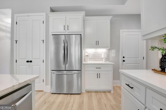192 Greyfairs Ave, Senoia, GA 30276 - kitchen with appliances with stainless steel finishes, light wood-style flooring, white cabinetry, and decorative backsplash
