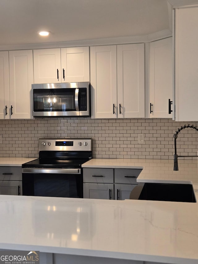 388 Kay Dr, Winder, GA 30680 - kitchen featuring stainless steel appliances, white cabinetry, tasteful backsplash, recessed lighting, and light stone counters