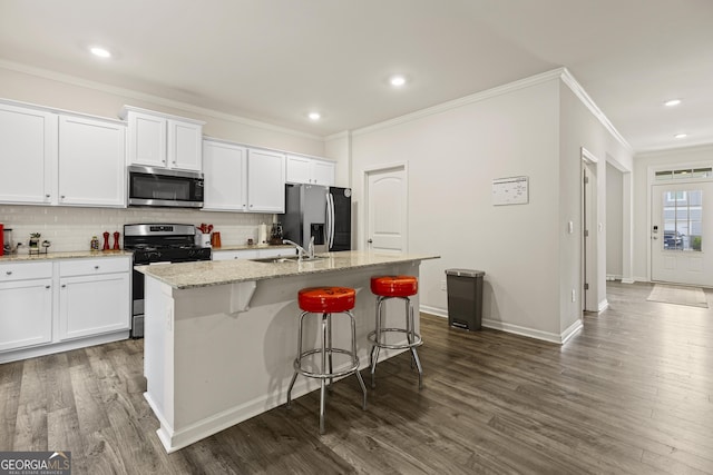 545 Quail Pass, Dawsonville, GA 30534 - kitchen featuring appliances with stainless steel finishes, ornamental molding, a kitchen island with sink, white cabinets, and decorative backsplash