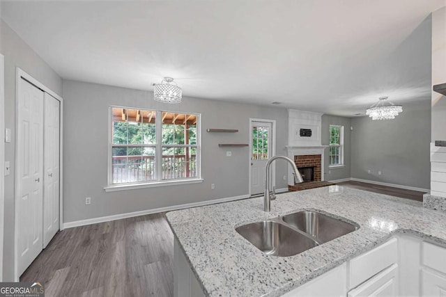1455 Holleybrooke Dr, Alpharetta, GA 30004 - kitchen featuring a chandelier, a fireplace, wood finished floors, light stone counters, and white cabinets