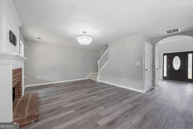 1455 Holleybrooke Dr, Alpharetta, GA 30004 - unfurnished living room with arched walkways, a brick fireplace, a chandelier, and wood finished floors