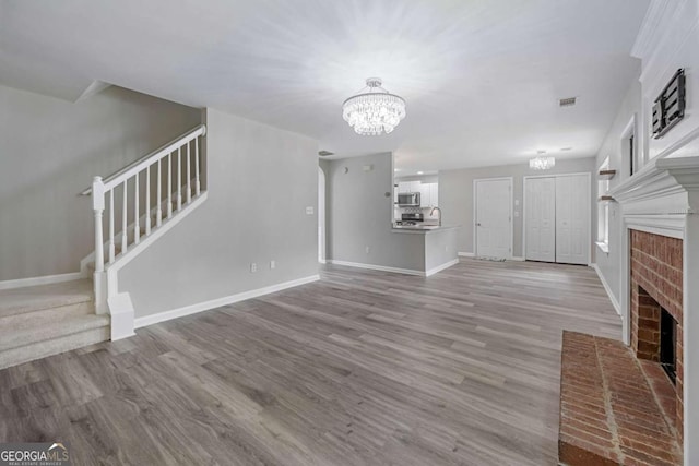 1455 Holleybrooke Dr, Alpharetta, GA 30004 - unfurnished living room featuring a chandelier, stairs, a fireplace, and wood finished floors