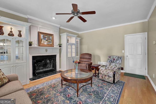7325 Brookwood Way, Cumming, GA 30041 - living area featuring ceiling fan, ornamental molding, light wood-style floors, and a fireplace with raised hearth