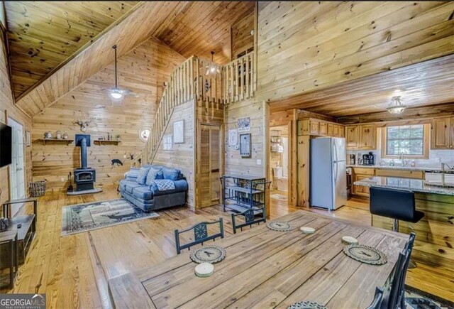 9947 Doublehead Gap Rd, Blue Ridge, GA 30513 - dining space featuring wooden walls, a wood stove, light wood finished floors, high vaulted ceiling, and wood ceiling
