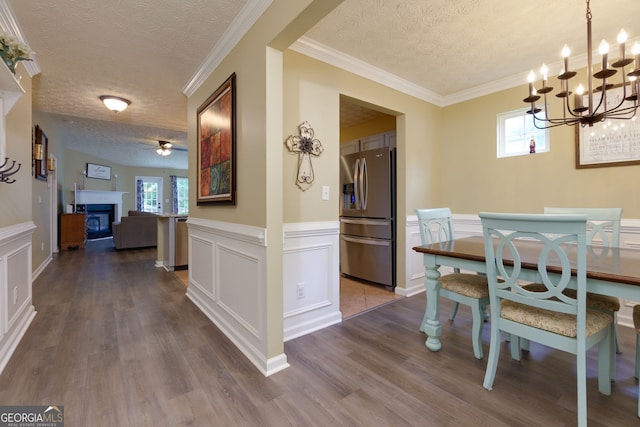 67 Granite Ct, Dallas, GA 30132 - dining space with a textured ceiling, a decorative wall, a chandelier, dark wood-type flooring, and a glass covered fireplace