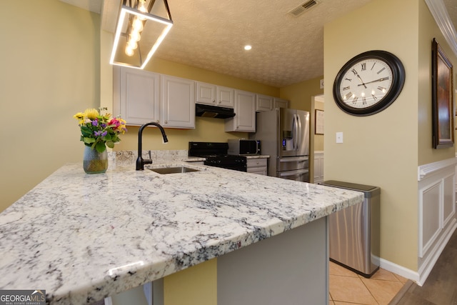 67 Granite Ct, Dallas, GA 30132 - kitchen with black gas range oven, under cabinet range hood, stainless steel refrigerator with ice dispenser, a peninsula, and light stone counters