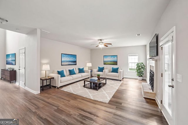 176 Windy Cir, Mcdonough, GA 30253 - living area with wood finished floors, ceiling fan, and a fireplace with raised hearth