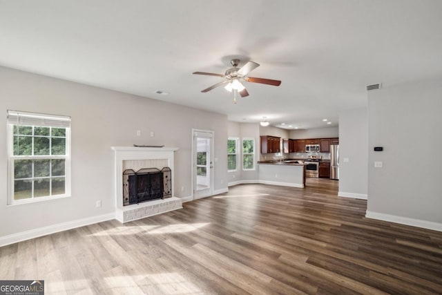 176 Windy Cir, Mcdonough, GA 30253 - unfurnished living room with a ceiling fan, dark wood-style flooring, plenty of natural light, a brick fireplace, and recessed lighting
