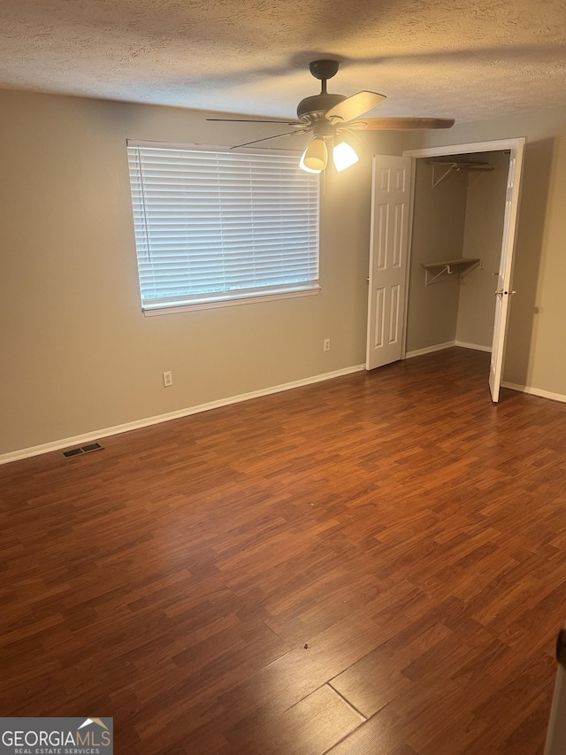5581 Marbut Rd, Lithonia, GA 30058 - unfurnished bedroom with a textured ceiling, dark wood-style flooring, ceiling fan, and a closet