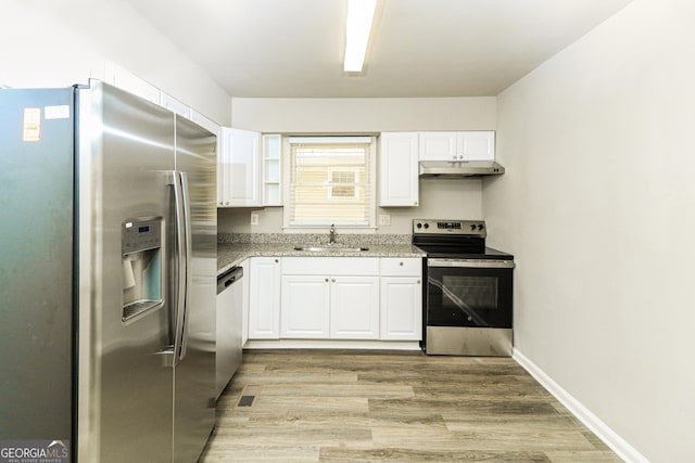 1947 Main St NW, Atlanta, GA 30318 - kitchen with appliances with stainless steel finishes, under cabinet range hood, white cabinetry, light wood-style floors, and light stone counters