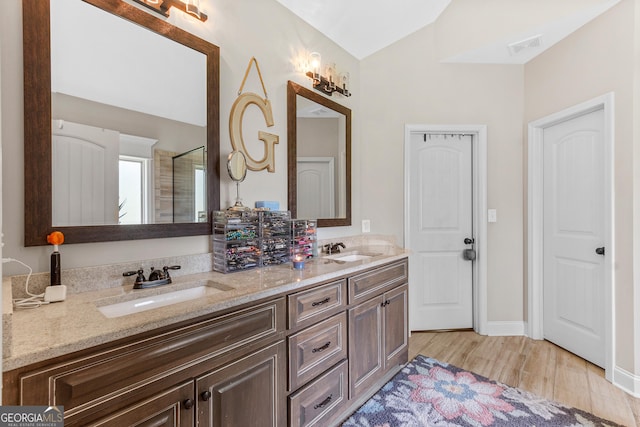 300 Bridgehampton Way, Perry, GA 31069 - bathroom featuring double vanity, wood finished floors, a shower, and vaulted ceiling