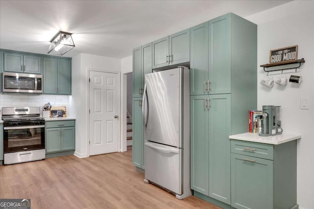 425 Shelby Ln, Hiram, GA 30141 - kitchen with stainless steel appliances, green cabinets, light wood finished floors, tasteful backsplash, and light countertops