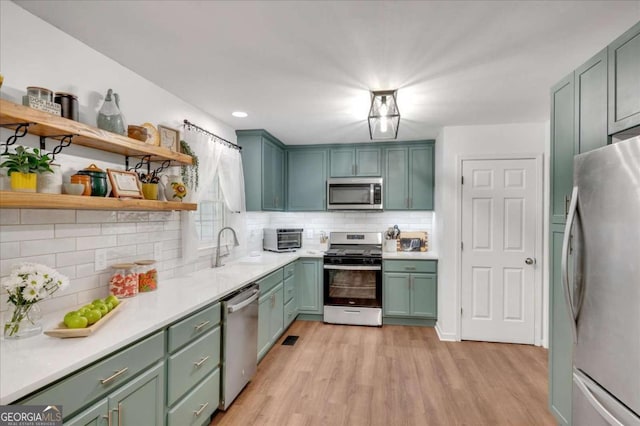 425 Shelby Ln, Hiram, GA 30141 - kitchen with appliances with stainless steel finishes, green cabinets, light wood-style flooring, decorative backsplash, and light countertops