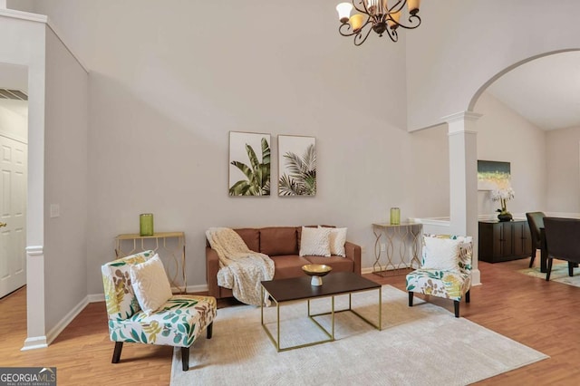 845 Melbourne Trl, Alpharetta, GA 30009 - living area with decorative columns, wood finished floors, arched walkways, a chandelier, and high vaulted ceiling