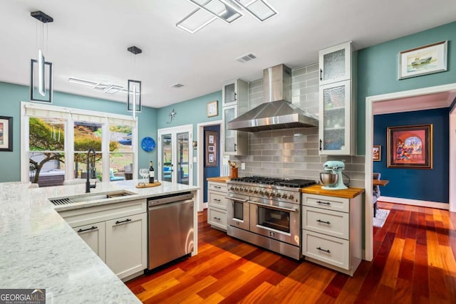 425 Starfire Ct, Suwanee, GA 30024 - kitchen featuring appliances with stainless steel finishes, wall chimney exhaust hood, decorative backsplash, white cabinets, and dark wood-style flooring
