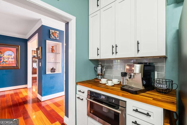425 Starfire Ct, Suwanee, GA 30024 - kitchen with wood counters, oven, decorative backsplash, wood finished floors, and ornamental molding