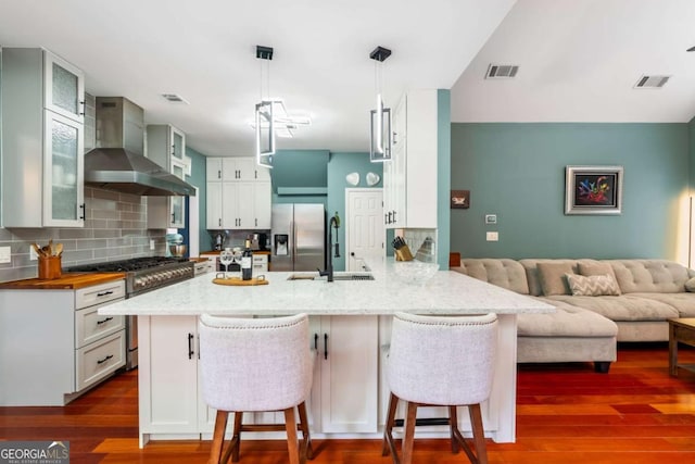 425 Starfire Ct, Suwanee, GA 30024 - kitchen with wall chimney exhaust hood, appliances with stainless steel finishes, tasteful backsplash, and a peninsula