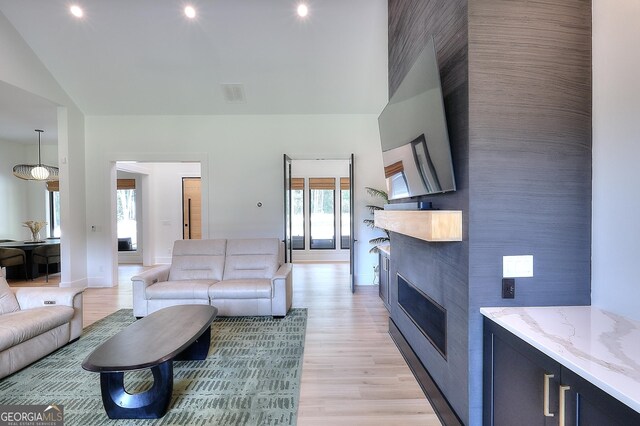 3960 Stock Rd SW, Monroe, GA 30656 - living area with healthy amount of natural light, light wood-type flooring, a glass covered fireplace, lofted ceiling, and recessed lighting