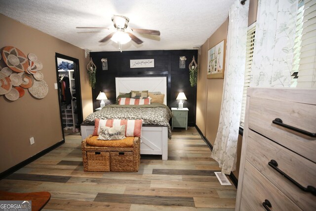 3227 Due W Rd, Dallas, GA 30157 - bedroom with wood finished floors, a walk in closet, a textured ceiling, and a ceiling fan