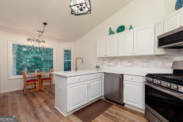 7140 Timberbrooke Dr, Gainesville, GA 30506 - kitchen with stainless steel appliances, a chandelier, a peninsula, decorative backsplash, and lofted ceiling